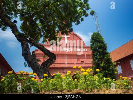 Malacca, Malaysia - August 10, 2022: Christ Church in the center of Melaka. Oldest functioning Protestant church in Malaysia. Past the trees and flowe Stock Photo