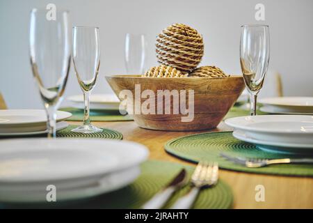 Close up white porcelain tableware plates on green place mats and empty champagne flutes ready for dinner. Table settings wait for guests at home or r Stock Photo