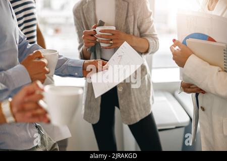 Close up of diverse coworkers analyzing sales report while having break in office Stock Photo