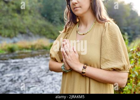 woman or witch performing magic ritual on river Stock Photo