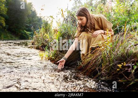 woman or witch performing magic ritual on river Stock Photo