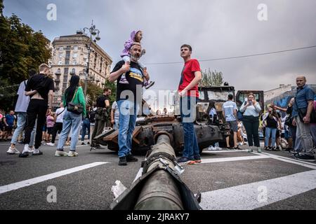 Kyiv, Ukraine. 20th Aug, 2022. Father, his son and daughter stand next to a tank turret while observing the wreckages of Russian military equipment in Kyiv, Ukraine. As dedicated to the upcoming Independence Day of Ukraine, and nearly 6 months after the full-scale invasion of Ukraine on February 24, the country's capital Kyiv holds an exhibition on the main street of Khreschaytk Street showing multiple destroyed military equipment, tanks, and weapons from The Armed Forces of The Russian Federation (AFRF). As the Russian full invasion of Ukraine started on February 24, the war has killed numer Stock Photo