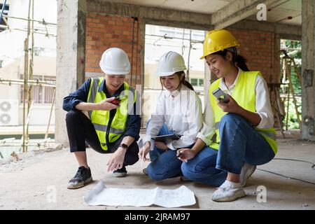 Structural engineer and architect discussing and working with blueprints at the outdoors construction site Stock Photo