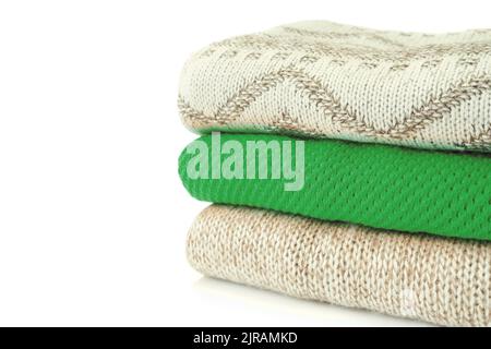 Stack of various knitted sweaters beige and green color isolated on white background with copy space for text Stock Photo