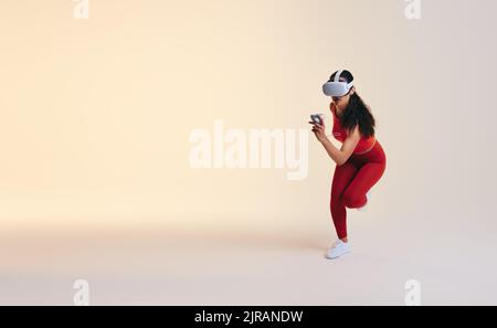 Young sportswoman woman running in virtual reality. Athletic young woman working out using 3D technology. Active young woman wearing a virtual reality Stock Photo