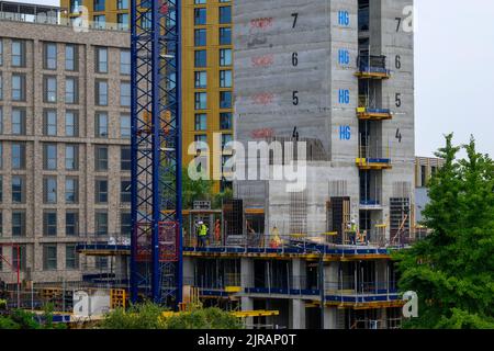Urban tower block project (modern high-rise multi-storey apartments development, trade people work, crane mast) - Leeds, West Yorkshire, England, UK. Stock Photo