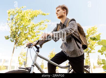 teenage boy with earphones and bag riding bicycle Stock Photo