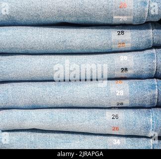 Photo of jeans in store. Stack of jeans on a shelf in a store. Stock Photo