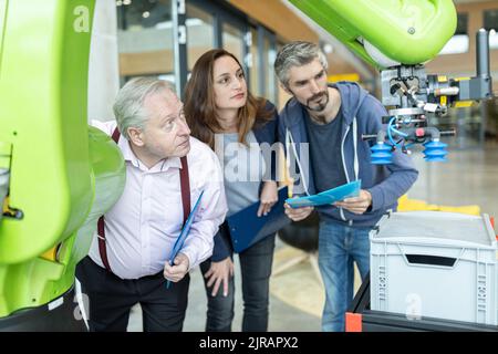 Technicians showing new industrial robot to senior colleague Stock Photo