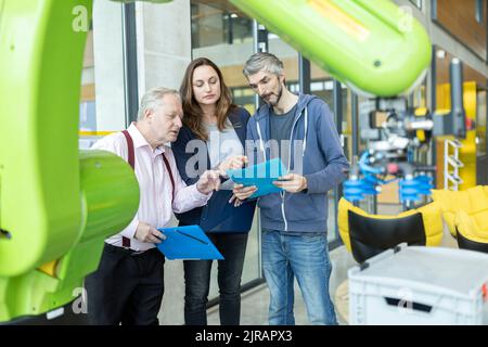 Technicians showing new industrial robot to senior colleague Stock Photo