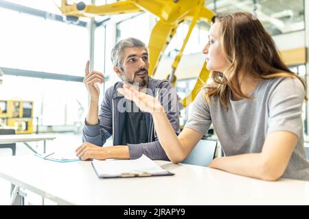 Technician and engineer sitting in factory discussing work solutions Stock Photo