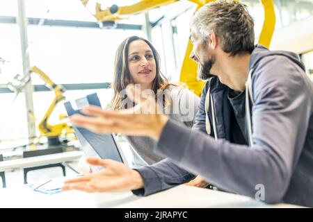 Technician and engineer sitting in factory discussing work solutions Stock Photo