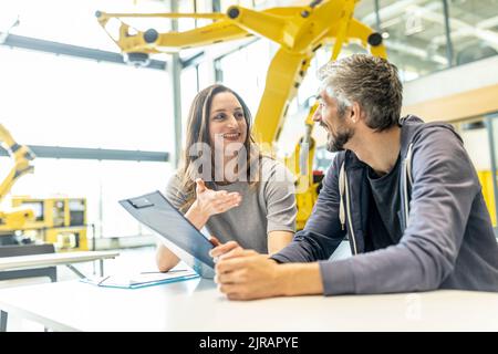 Technician and engineer sitting in factory discussing work solutions Stock Photo