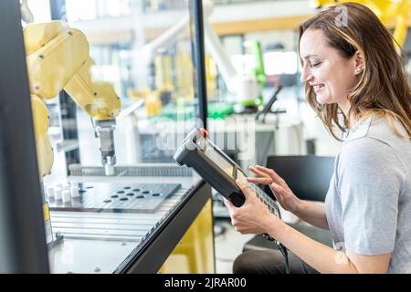 Woman in factory using control of industrial robot Stock Photo