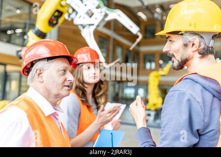 Senior colleague in work wear having meeting with skilled workers Stock Photo