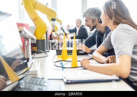 Engineers in factory developing new robot arm Stock Photo