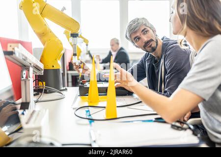 Engineers in factory developing new robot arm Stock Photo