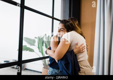 Businesswomen hugging each other in office Stock Photo