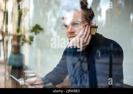 Thoughtful mature businessman holding credit card sitting in cafe Stock Photo
