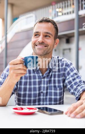 Smiling mature man drinking coffee at sidewalk coffee Stock Photo