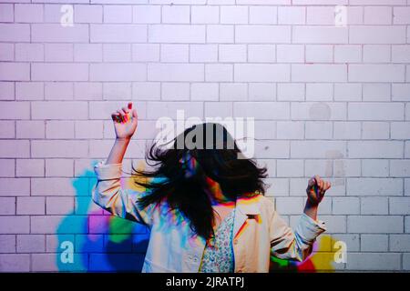 Young woman dancing in front of wall Stock Photo