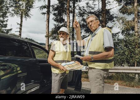 Senior engineer talking with colleague standing by car Stock Photo