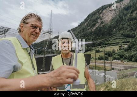Smiling engineer discussing over wind turbine model Stock Photo