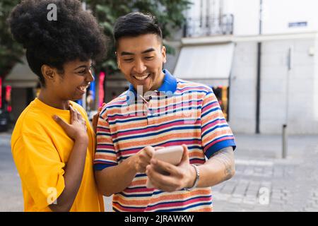 Cheerful young woman looking at man using smart phone Stock Photo