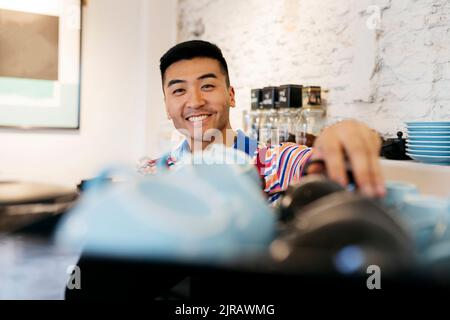 Smiling young man working in coffee shop Stock Photo