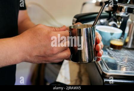 Hand of man holding mug making coffee in cafe Stock Photo