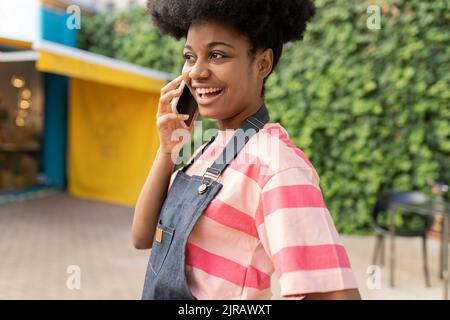 Happy woman with Afro hairstyle talking on smart phone Stock Photo