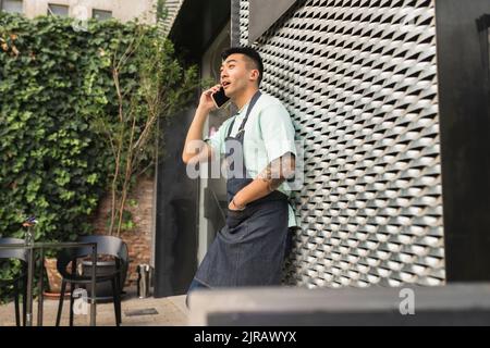 Surprised man talking through mobile phone leaning on wall Stock Photo