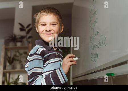 Smiling boy with felt tip pen by whiteboard at home Stock Photo