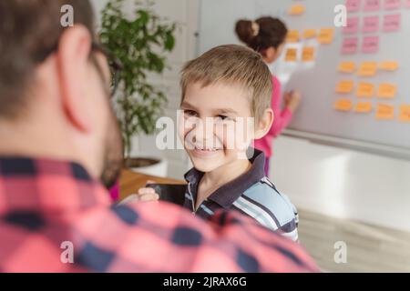 Smiling boy looking at teacher in tuition Stock Photo