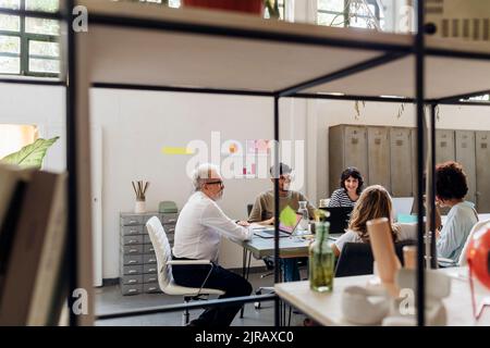 Multiracial coworkers talking to each other at office Stock Photo