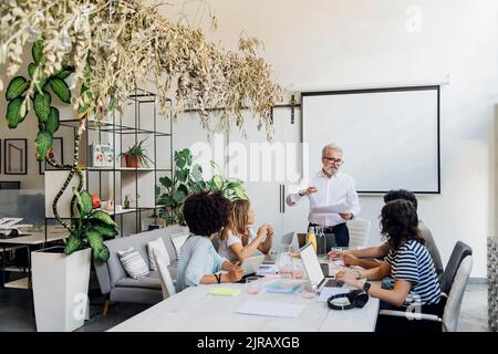 Manager explaining to coworkers in business meeting at office Stock Photo