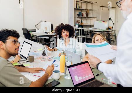 Multiracial workers looking at manager reviewing report in meeting at office Stock Photo