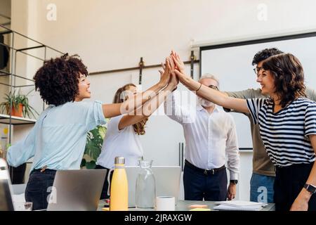 Cheerful business colleagues giving high-five to each other at office Stock Photo