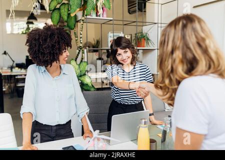 Smiling colleague shaking hand with manager at office Stock Photo
