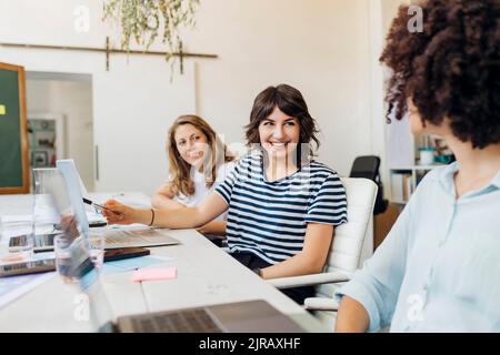 Happy business colleagues planning together at work place Stock Photo