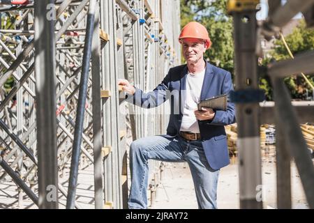Smiling engineer with tablet PC standing by scaffolding Stock Photo