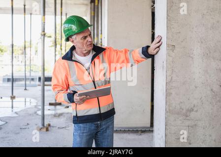 Senior contractor with tablet PC examining column Stock Photo