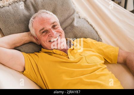 Happy man with hand behind head relaxing in hammock Stock Photo