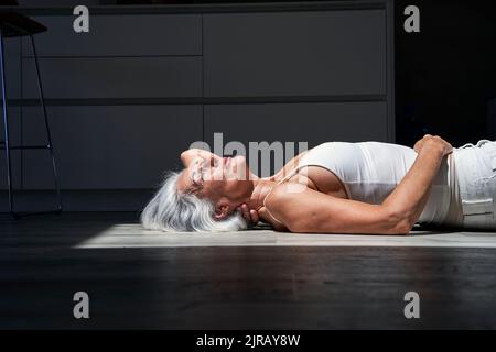 Woman lying down on floor at home Stock Photo