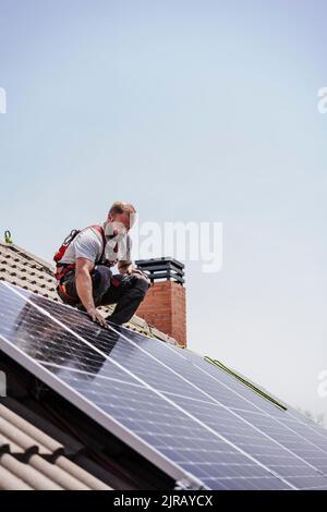 Electrician installing solar panels on roof Stock Photo