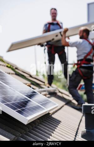 Electricians installing solar panels on house roof Stock Photo