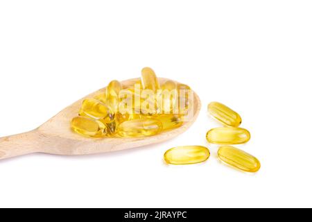 Pile of softgels capsules Omega 3 in wooden spoon isolated on white background. Close up with copy space Stock Photo