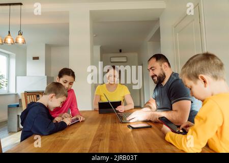 Parents with children using wireless technologies at home Stock Photo