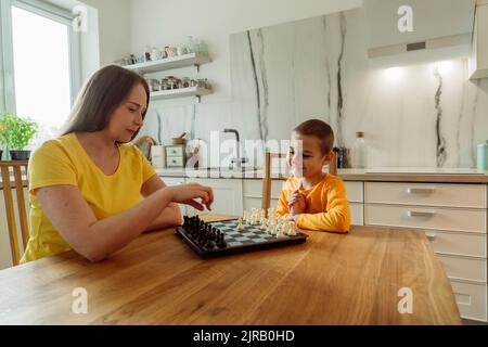 Mother and son playing chess in domestic kitchen Stock Photo