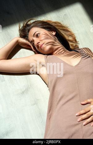 Woman lying down on floor in sunlight Stock Photo
